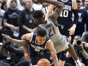 Villanova's Phil Booth, bottom, tangles with Connecticut's Mamadou Diarra after pulling down a rebound during the first half of an NCAA college basketball game, Saturday, Jan. 20, 2018, in Hartford, Conn.