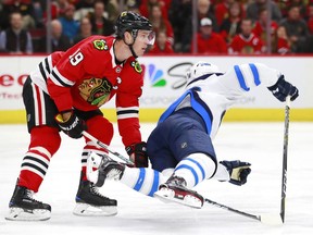 Chicago Blackhawks center Jonathan Toews (19) trips Winnipeg Jets center Marko Dano during the first period of an NHL hockey game Friday, Jan. 12, 2018, in Chicago.