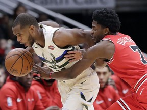 Milwaukee Bucks forward Khris Middleton, left, drives against Chicago Bulls guard Justin Holiday during the first half of an NBA basketball game Sunday, Jan. 28, 2018, in Chicago.