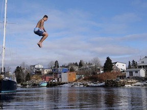 A man jumps off a wharf into the Atlantic Ocean during the Herring Cove Polar Bear Dip in Herring Cove, N.S., on Monday, January 1, 2018.