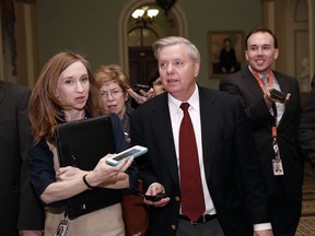 Sen. Lindsey Graham, R-S.C., front right, walks as he is questioned by reporters on Capitol Hill, Friday, Jan. 19, 2018, in Washington.