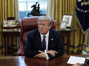 President Donald Trump sits at the Resolute Desk after signing Section 201 actions in the Oval Office of the White House in Washington, Tuesday, Jan. 23, 2018. Trump says he is imposing new tariffs to "protect American jobs and American workers." Trump acted to impose new tariffs on imported solar-energy components and large washing machines in a bid to help U.S. manufacturers.