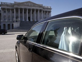 Extra shirts hang inside of a senator's vehicle as the Capitol dome is reflected on Capitol Hill as a bitterly-divided Congress hurtles toward a government shutdown this weekend, Friday, Jan. 19, 2018, in Washington.