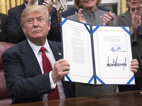 U.S. President Donald Trump displays a signed bill in the Oval Office on Wednesday, Jan. 10, 2018.
