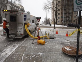 Crews work near a manhole cover in Edmonton Alta, on Wednesday January 10, 2018. A woman was taken to hospital early Wednesday after she fell down a manhole that had blown open in an electrical explosion in downtown Edmonton.