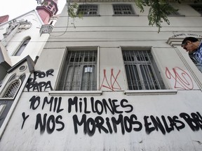 A man walks past a building defaced with a message that reads in Spanish: "10 million for the Pope (to travel) and we die in our towns', in Santiago, Chile, Friday, Jan. 12, 2018. Chilean President Michelle Bachelet is asking the country to receive Pope Francis in a "climate of respect," hours after three Roman Catholic churches were firebombed and a note left at the scene threatening the pontiff.