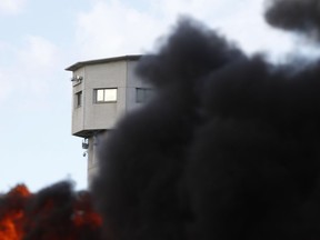 Smoke rises as a fire set up by penitentiary staff outside the prison in Vendin le Vieil, northern France, Tuesday, Jan.16, 2018. Protesting French prison guards have pushed back against riot police and shouted down the justice minister amid demonstrations at several prisons over violent inmates and overcrowding.