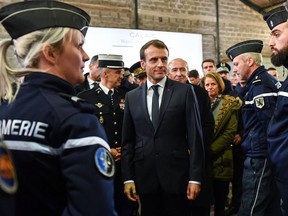 French President Emmanuel Macron, center, speaks with French gendarmes during his visit to Calais, northern France, Tuesday, Jan.16, 2018. Macron traveled Tuesday to the epicenter of France's migrant crisis, the northern port of Calais, to lay out a "humane and tough" immigration policy that involved better behavior by security forces and closer cooperation with Britain.