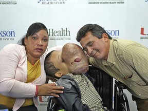 FILE - In this Dec. 22, 2017, file photo, Emanuel Zayas, 14, sits with his parents Noel Zayas and Melvis Vizcainos at Holtz Children's Hospital at Jackson Memorial in Miami. Emanuel Zayas died Friday, Jan. 19, 2018, days after doctors removed a 10-pound tumor from his face.