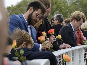 Tal Ramon, left with sunglasses, son of space shuttle Columbia astronaut Ilan Ramon, and other friends and family of fallen astronauts place flowers in the fence at the Space Mirror Memorial at Kennedy Space Center Visitor Complex Thursday, Jan 25, 2018, during Kennedy Space Center's annual day of remembrance. The annual event honors those who perished in the space program.