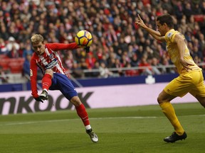 Atletico Madrid's Antoine Griezmann, left, shoots the ball next to Girona's Bernardo Espinosa during a Spanish La Liga soccer match between Atletico Madrid and Girona at the Wanda Metropolitano stadium in Madrid, Saturday, Jan. 20, 2018.