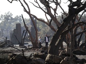 A woman and a man stand in front of a structure damaged from storms in Montecito, Calif., Thursday, Jan. 11, 2018.  Hundreds of rescue workers slogged through knee-deep ooze and used long poles to probe for bodies Thursday as the search dragged on for victims of the mudslides that slammed this wealthy coastal town.