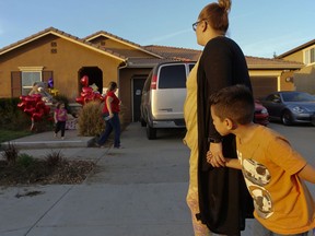 File - In this Jan. 18, 2018 file photo, neighbor Avery Sanchez, 6, peeks behinds his mother, Liza Tozier after dropping off his large "Teddy" for the children who lived on a home where police arrested a couple on Sunday accused of holding 13 children captive in Perris, Calif. The community college student with a page-boy haircut was quiet and never drew attention to himself and scored A's semester after semester. Despite ample opportunity, he apparently never divulged the sickening truth that the home he returned to after classes was a veritable torture chamber. Authorities say the man, now about 26, was the eldest boy among 13 siblings who were held captive in their Southern California home by their parents, David and Louise Turpin.