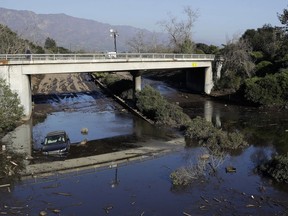 A car sits in flooded water on Highway 101 in Montecito, Calif., Thursday, Jan. 11, 2018. Rescue workers slogged through knee-deep ooze and used long poles to probe for bodies Thursday as the search dragged on for victims of Tuesday's storm after mudslides slammed this wealthy coastal town.