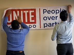 In this photo taken Monday, Jan. 22, 2018, Dominick Scafidi, left, in charge of field and digital operations and Jake Wiegman, right, special projects manager put up a sign during a brainstorming session at the Unite America office in Denver. The constant fighting in Washington is giving new motivations to groups trying to lower the importance of partisanship in U.S. politics. Unite America is recruiting candidates to run as nonpartisans for various U.S. Senate and governors seats.