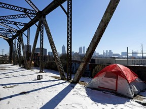 A tent sits in the snow on a bridge frequented by the homeless as the downtown skyline stands in the background in Atlanta, Thursday, Jan. 18, 2018. The deep freeze that shut down much of the South began to relent Thursday as crews worked to clear roads blanketed by a slow-moving storm that left ice and snow in places that usually enjoy mild winters.