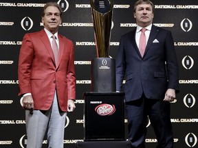 Alabama head coach Nick Saban, left, and Georgia head coach Kirby Smart pose with the NCAA college football championship trophy at a press conference in Atlanta, Sunday, Jan. 7, 2018. Georgia and Alabama will be playing for the championship on Monday, Jan. 8.