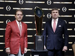 Alabama head coach Nick Saban, left, and Georgia head coach Kirby Smart pose with the NCAA college football championship trophy at a press conference in Atlanta, Sunday, Jan. 7, 2018. Georgia and Alabama will be playing for the championship on Monday, Jan. 8.