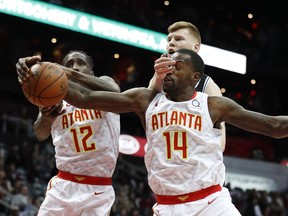 Atlanta Hawks' Dewayne Dedmon (14) and Taurean Prince (12) battle San Antonio Spurs forward Davis Bertans (42) for the ball in the first half of an NBA basketball game Monday, Jan. 15, 2018, in Atlanta.