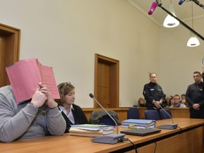 In this Feb. 26, 2015 file photo former nurse Niels Hoegel, accused of multiple murder and attempted murder of patients, covering his face with a file at the district court in Oldenburg, Germany.
