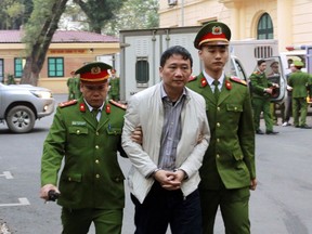 Trinh Xuan Thanh, center, is led to a court room by police in Hanoi, Vietnam, Monday, Jan. 22, 2018. The former oil executive was sentenced to life in prison on charges of embezzlement and mismanagement at the end of the two-weeks trial that also involves 21 others including former Politburo Dinh La Thang. Germany accused Vietnam of kidnapping Thanh from a Berlin park in July, the charge Vietnam denied saying Thanh turned himself in to police voluntarily.