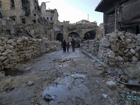 In this picture taken Sunday, Jan. 21, 2018, a Syrian family walks through the destruction of the old market in the old city of Aleppo, Syria. Fighting has long died down in Syria's largest city but Aleppo's centuries-old market still has to come back to life, more than a year after government forces retook rebel-held neighborhoods around the Old City.