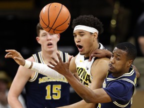 Iowa forward Cordell Pemsl fights for a rebound with Michigan guard Muhammad-Ali Abdur-Rahkman, right, during the first half of an NCAA college basketball game, Tuesday, Jan. 2, 2018, in Iowa City, Iowa.