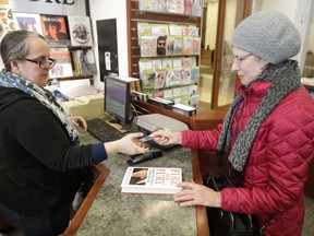 Rebecca Burgess, left, sells a copy of the book "Fire and Fury: Inside the Trump White House" by Michael Wolff to Susan Vander Veer,  from Peotone, Ill., at Barbara's Books Store, Friday, Jan. 5, 2018, in Chicago.