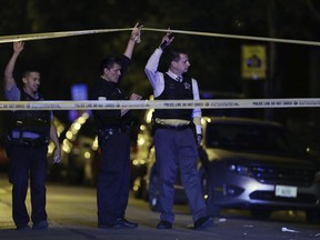 FILE - In this Sept. 2, 2017, file photo, police lift crime scene tape after two people were shot and transported to Stroger Hospital in Chicago. Chicago ended 2017 with fewer homicides than the year before but raging gang wars in the city's most violent neighborhoods drove the total beyond the 600 mark for just the second time in well over a decade.