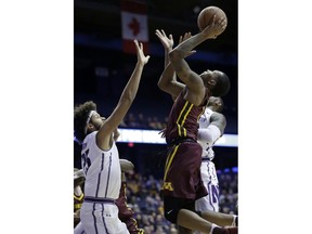 Minnesota guard Dupree McBrayer, center, goes up for a shot against Northwestern center Barret Benson, left, and guard Jordan Ash during the first half of an NCAA college basketball game Wednesday, Jan. 10, 2018, in Rosemont, Ill.