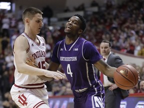 Northwestern's Vic Law (4) is fouled by Indiana's Zach McRoberts during the first half of an NCAA college basketball game, Sunday, Jan. 14, 2018, in Bloomington, Ind.