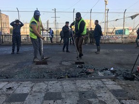 Baghdad municipality workers clean the scene of a double suicide bombing in Baghdad, Iraq, Monday, Jan. 15, 2018. Interior Ministry spokesman said a double suicide bombing in central Baghdad has killed and wounded civilians.