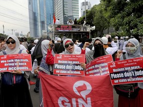 A group of Muslim women hold posters during a rally outside the Facebook office in Jakarta, Indonesia, Friday, Jan. 12, 2018. Muslim hard-liners have staged protest against the social media giant Facebook in Indonesia's capital over its alleged ban on multiple pages and accounts related to their group.