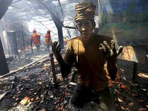 A scorched statue sists in the ashes as a fireman tries to extinguish parts of a huge fire that spread through the Maritime Museum in Jakarta, Indonesia, Tuesday, Jan. 16. 2018. A fire broke out in the Maritime Museum in northern Jakarta Tuesday morning, partially destroying Dutch colonial-era buildings there Indonesian authorities said.