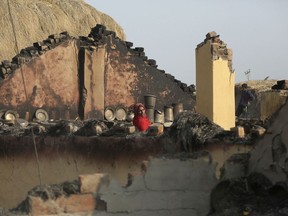 Indian woman inspects damage and collects goods from the family home, after it was gutted by firing from the Pakistan side of the border in Jora farm village 35 kilometers (22 miles) in Ranbir Singh Pura district of Jammu and Kashmir, India, Sunday, Jan. 21, 2018.  The villages are almost deserted along the international border as almost the entire population have moved to safer ground away from the volatile border region.