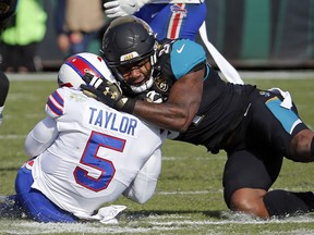 Jacksonville Jaguars defensive end Yannick Ngakoue, right, draws a penalty by hitting Buffalo Bills quarterback Tyrod Taylor (5) with helmet-to-helmet contact in the first half of an NFL wild-card playoff football game, Sunday, Jan. 7, 2018, in Jacksonville, Fla.