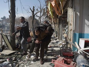 Afghan volunteers carry a body at the scene of a car bomb exploded in front of the old Ministry of Interior building in Kabul on Jan 27, 2018.