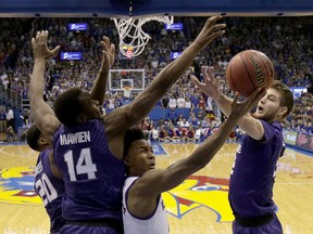 Kansas' Devonte' Graham shoots under pressure from Kansas State's Dean Wade, right, Xavier Sneed (20) and Makol Mawien (14) during the first half of an NCAA college basketball game Saturday, Jan. 13, 2018, in Lawrence, Kan.