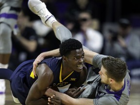West Virginia forward Wesley Harris, left, lands on the ball while covered by Kansas State forward Dean Wade, right, during the first half of an NCAA college basketball game in Manhattan, Kan., Monday, Jan. 1, 2018.