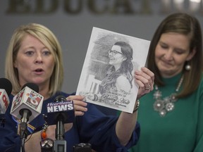 Tracy Tubbs, left, aunt of Marshall County High School shooting victim Bailey Holt, holds up a drawing of Holt as Tubbs and Jackie Reid, right, principal of Sharpe Elementary School in Benton, Ky., read statements from Holt and Preston Cope's families at the Marshall County Board of Education in Benton, Ky., Saturday, Jan. 27, 2018.