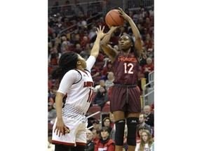 Virginia Tech guard Chanette Hicks (12) shoots over the defense of Louisville guard Arica Carter (11) during the first half of an NCAA college basketball game, Sunday, Jan. 7, 2018, in Louisville, Ky.