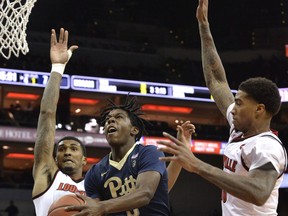 Pittsburgh guard Marcus Carr (5) splits the defense of Louisville forward Malik Williams (5) and forward Ray Spalding (13) as he drives to the basket during the first half of an NCAA college basketball game, Tuesday, Jan. 2, 2018, in Louisville, Ky.