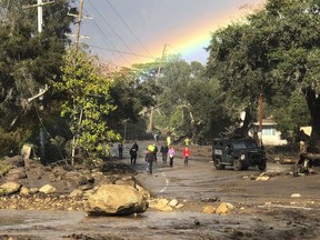 In this photo provided by Santa Barbara County Fire Department, shows a rainbow forming above Montecito, Calif. while law enforcement and the curious survey the destruction on Hot Springs Road on Tuesday, Jan. 9, 2018. Homes were swept away before dawn Tuesday when mud and debris roared into neighborhoods in Montecito from hillsides stripped of vegetation during a recent wildfire.