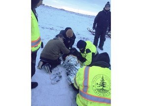 This January, 2018 photo provided by Bethel Search and Rescue shows team members helping a person suffering from hypothermia on a portion of the Kuskokwim River near Bethel, Alaska. The river is not covered by as much ice as it usually is this time of year. Months of higher-than-normal temperatures have opened dangerous holes in frozen rivers that rural Alaskans use as roads. One troublesome ice highway is the Kuskokwim River, where a man died New Year's Eve after driving his snowmobile into a hole. (Bethel Search and Rescue via AP)