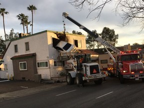 In this Sunday, Jan. 14, 2018, photo provided by Orange County Fire Authorit, a vehicle that crashed into a building hangs from a second story window in Santa Ana, Calif. Members from Orange County Fire Authority and Los Angeles County Urban Search & Rescue rescued two people, who escaped serious injuries when the car they were in went airborne and slammed into the second floor of a dental office in Southern California. Authorities say the Nissan Altima hit a center divider early Sunday, soared into the air and plowed into the top floor of the two-story structure.