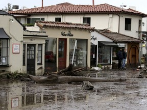 FILE - In this Tuesday, Jan. 9, 2018 file photo, debris and mud cover the street in front of local area shops after heavy rain brought flash flooding in Montecito, Calif. Officials said that it will be a gradual process getting residents back into homes in Montecito.