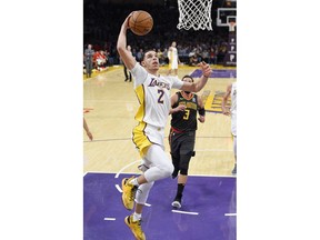 Los Angeles Lakers guard Lonzo Ball, left, goes up for a dunk as Atlanta Hawks guard Marco Belinelli, of Italy, watches during the second half of a basketball game, Sunday, Jan. 7, 2018, in Los Angeles. The Lakers won 132-113.