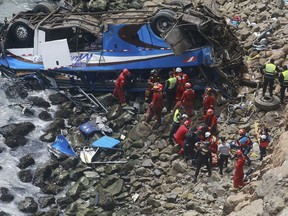 EDS NOTE GRAPHIC CONTENT - In this photo provided by the government news agency Andina, firemen recover bodies from a bus that fell off a cliff after it was hit by a tractor-trailer rig, in Pasamayo, Peru, Tuesday, Jan 2, 2018. A Peruvian police official says at least 25 people died, and that there were more than 50 people on the bus.