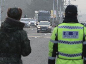 A South Korean soldier, left, and a police officer stand as vehicles carrying the South Korean delegation pass near Unification Bridge, which leads to the Panmunjom in the Demilitarized Zone in Paju, South Korea, Wednesday, Jan. 17, 2018. South Korean delegation departed for Panmunjom on Wednesday morning for talks with North Korea to further discuss the North's paricipation in the upcoming Winter Olympics.