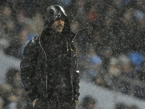 Manchester City's manager Pep Guardiola watches in heavy rain during the English Premier League soccer match between Manchester City and Watford at Etihad stadium, in Manchester, England, Tuesday, Jan. 2, 2018.